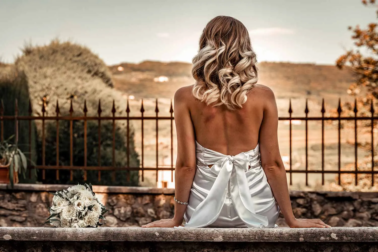 Bride looking out over the Lake Garda hills, wedding dress bow detail — oemme photography