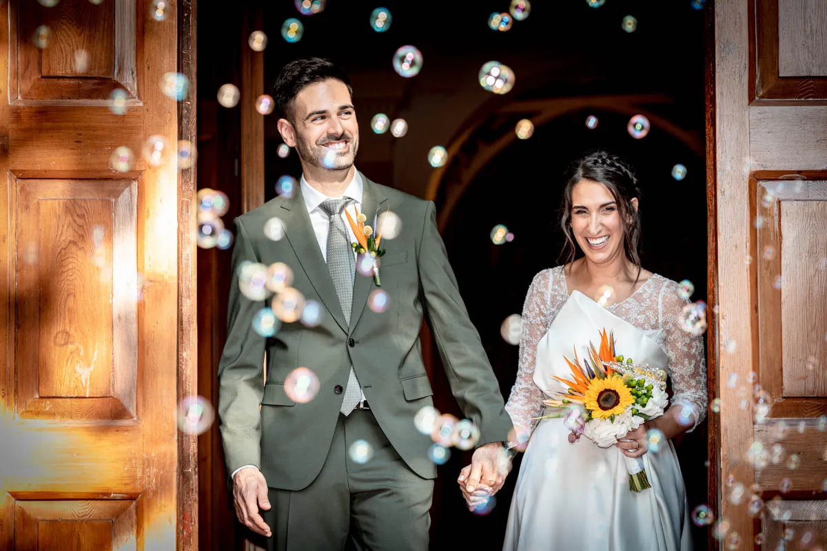 Newlyweds laughing through a shower of bubbles as they leave the church — oemme photography